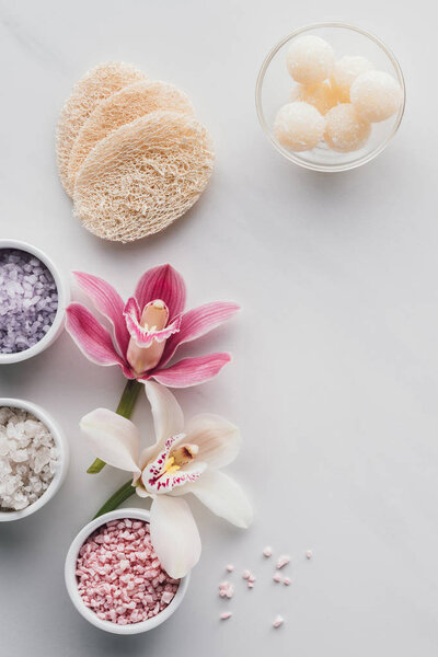 beautiful orchid flowers, sea salt in bowls and sponges on white background 