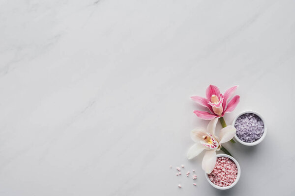 top view of beautiful orchid flowers and sea salt in bowls on white background