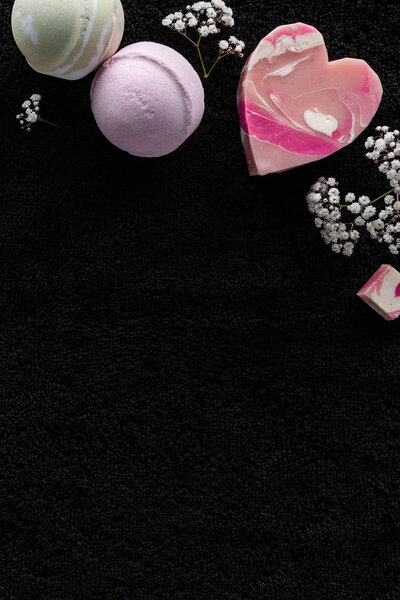 верхний вид на мыло ручной работы и красивые маленькие белые цветы на черном фоне
