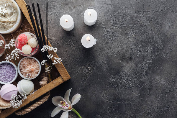 вид на спа и банные принадлежности в деревянной коробке и горящие свечи на сером фоне
 