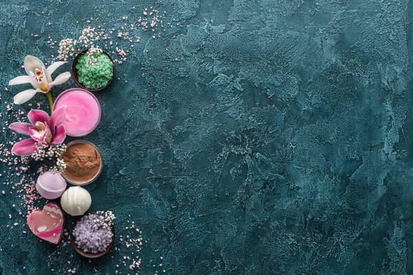 вид сверху на орхидеи, морскую соль и мыло ручной работы на темном фоне
