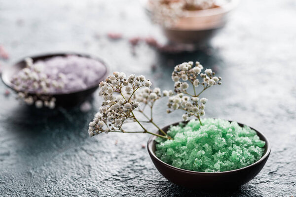 close-up view of sea salt in bowls and small white flowers, selective focus