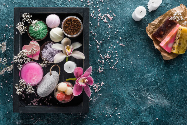 вид сверху на спа-аксессуары в коробке и свечи с домашним мылом
