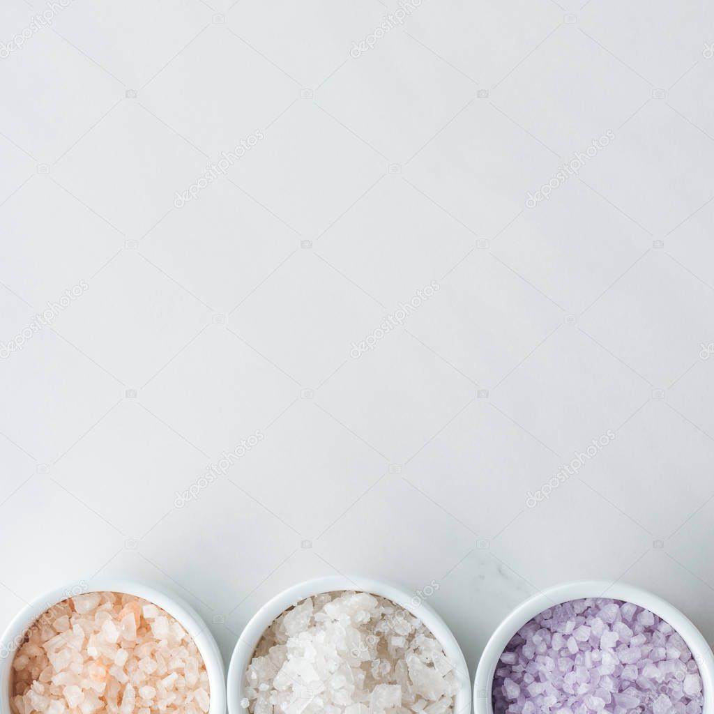 top view of colorful sea salt in bowls on white background 