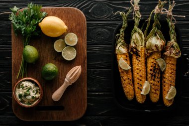 kesme tahtası kireç dilimleri, limon, maydanoz ile krem, Sıkacağı ızgara Mısır ile zor durumda pan yakınındaki üstten görünüm ahşap tablo 