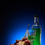 Close-up shot of absinthe with grapes and dorblu cheese on mirror surface on dark blue background