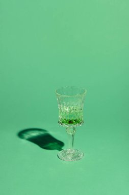 crystal glass of absinthe beverage on green surface clipart