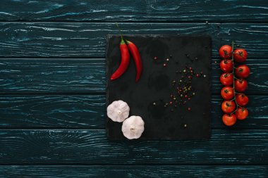 top view of vegetables and chilli peppers on stone cutting board on green wooden tabletop clipart