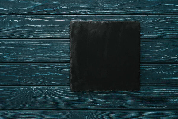 вид сверху на черную доску для резки камня на зеленом деревянном столе
