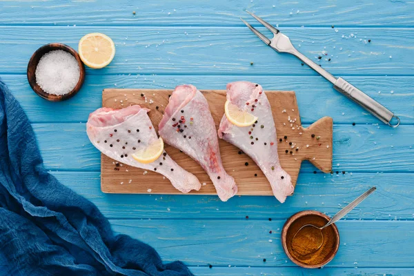Top View Chicken Legs Wooden Board Pepper Corns Blue Tabletop — Stock Photo, Image