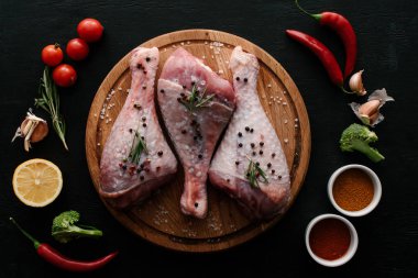 flat lay with turkey legs on wooden cutting board with vegetables and spices clipart