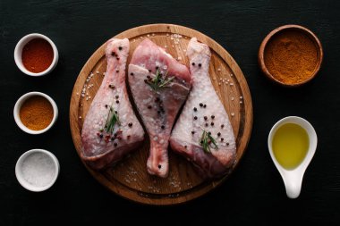 top view of turkey legs on cutting board with oil, paprika and salt clipart