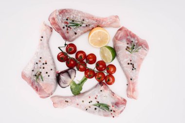 top view of turkey legs with cherry tomatoes, lime and lemon, isolated on white clipart