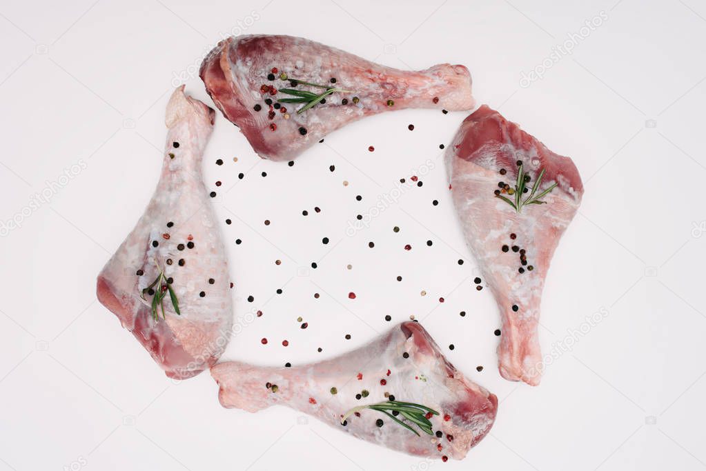 top view of raw turkey legs with pepper corns and rosemary, isolated on white