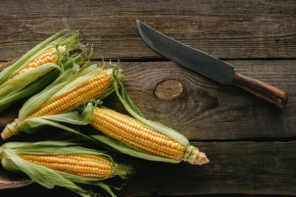 Draufsicht Auf Frische Rohe Maiskolben Und Messer Auf Hölzerner Tischplatte — Stockfoto