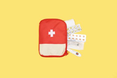 top view of automotive first aid kit with different medicines isolated on yellow clipart