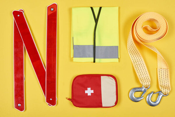 flat lay with arranged first aid kit and automotive accessories isolated on yellow