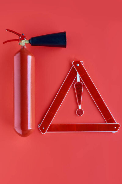 top view of fire extinguisher and warning triangle isolated on red
