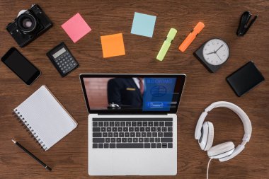 ahşap masa boş ders kitabı, smartphone, fotoğraf makinesi ve laptop ile rezervasyon ekranda üstten görünüm