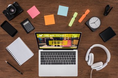 ahşap masa boş ders kitabı, smartphone, fotoğraf makinesi ve online bilet ile dizüstü bilgisayar ile ekranda yukarıdan