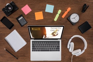 ahşap masa boş ders kitabı, smartphone, fotoğraf makinesi ve online bilet ile dizüstü bilgisayar ile ekranda yukarıdan