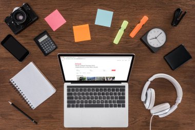 ahşap masa boş ders kitabı, smartphone, fotoğraf makinesi ve airbnb ile dizüstü bilgisayar ile ekranda yukarıdan