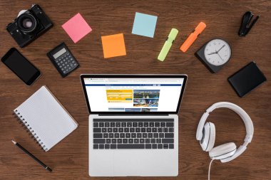 ahşap masa boş ders kitabı, smartphone, fotoğraf makinesi ve booking.com ile dizüstü bilgisayar ile ekranda yukarıdan