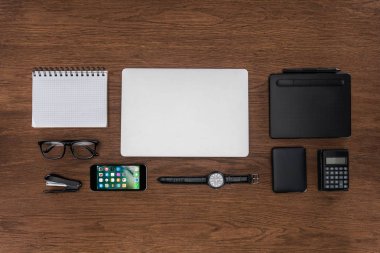 çalışma alanı görücü usulü boş ders kitabı, dizüstü bilgisayar, kol saati ve iphone ile üstten görünüm ahşap tablo 