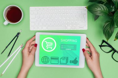 kadın mimar masada bölücü, kahve ve Saksı bitki ile ekranda alışveriş ile dijital tablet tutan kırpılmış görüntü 