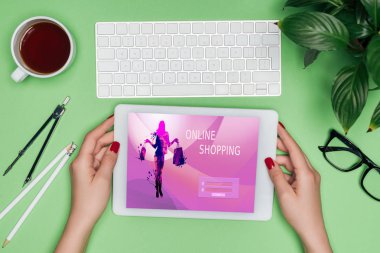 kadın mimar masada bölücü, kahve ve Saksı bitki ile ekranda online alışveriş ile dijital tablet tutan kırpılmış görüntü 