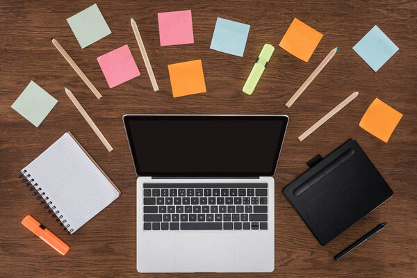 top view of workplace with arranged textbooks, post it and laptop with blank screen 