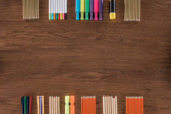 top view of arranged colorful pencils and markers on wooden table 