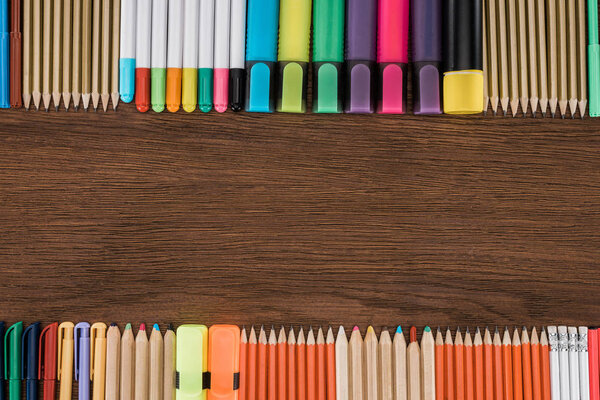 elevated view of arranged colorful pencils and markers on wooden table 