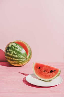close up view of slice of watermelon on plate on pink background clipart