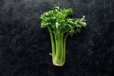 top view of fresh green celery on black marble surface clipart