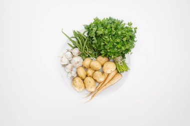 top view of arranged ripe vegetables on plate isolated on white clipart
