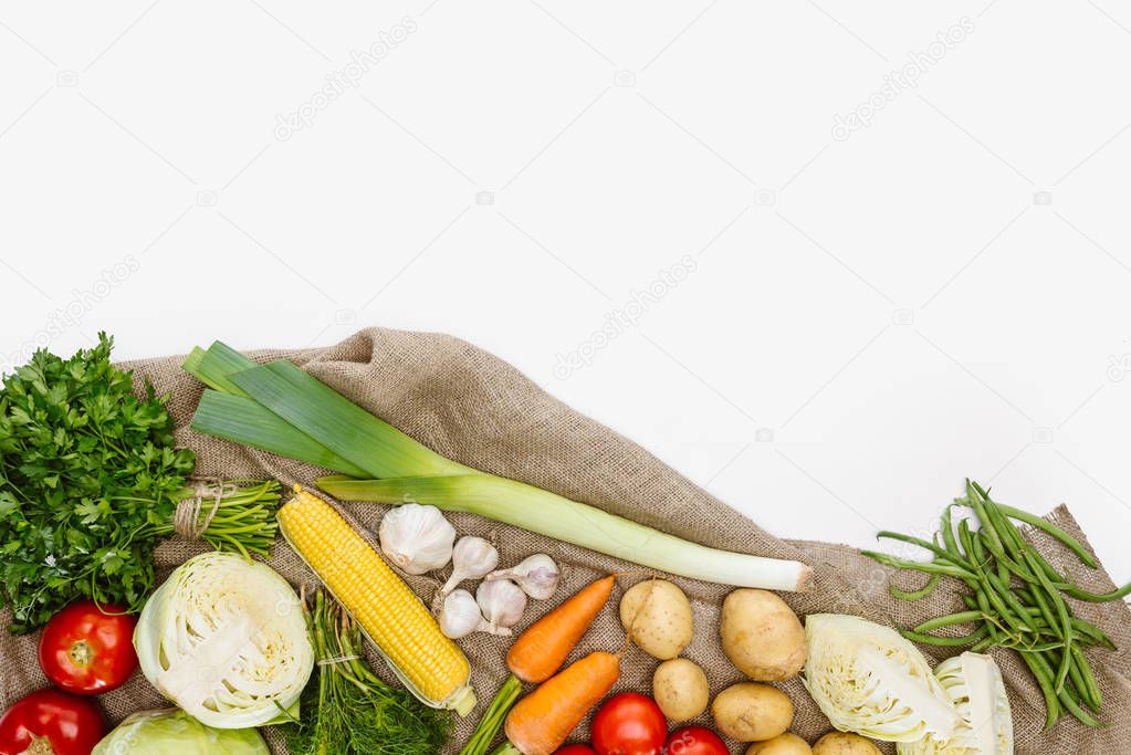 food composition with fresh vegetables arranged on sackcloth isolated on white