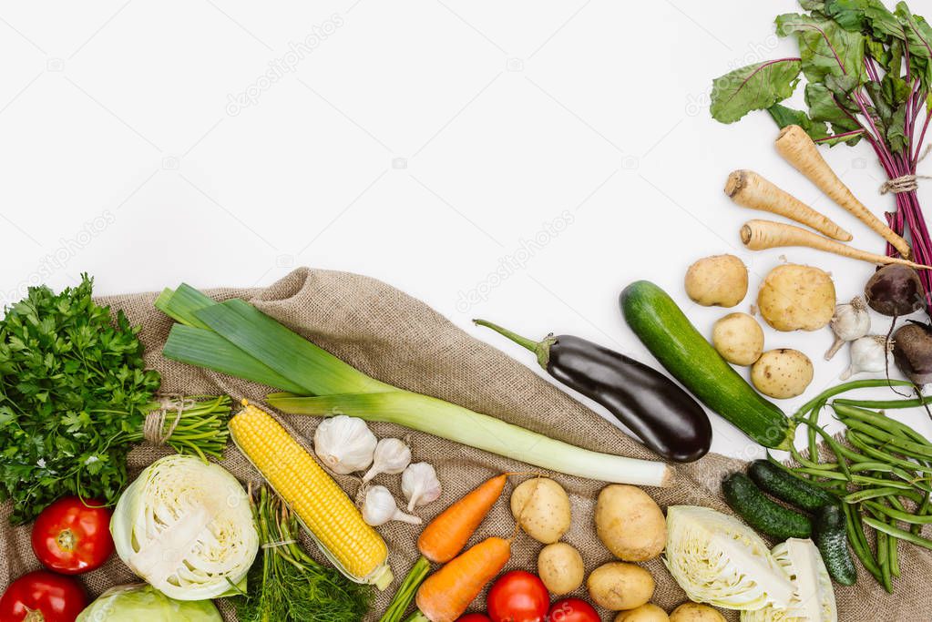 food composition with fresh vegetables arranged on sackcloth isolated on white