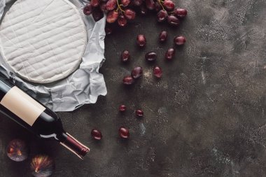 -bir şişe şarap, brie peyniri, incir ve üzüm üstten görünüm karanlık yüzeyi