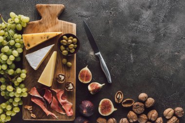 düz lay çeşitli peynir, jamon, üzüm, fındık ve incir karanlık yüzeyi ile