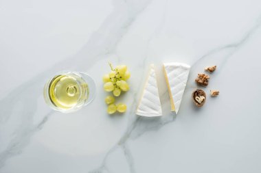 düz lay kadeh şarap, camembert peyniri ve fındık beyaz mermer yüzeyi ile