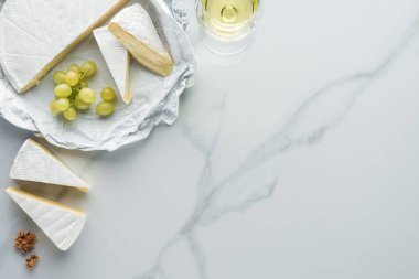 düz lay kadeh şarap, camembert peyniri ve üzüm beyaz mermer yüzeyi ile