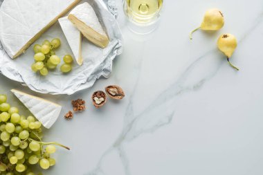 düz lay kadeh şarap, camembert peyniri, armut ve üzüm beyaz mermer yüzeyi ile