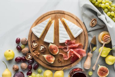 düz lay peynir, jamon, incir, fındık ve beyaz mermer masa üzerinde ahşap tahta üzerinde üzüm ile