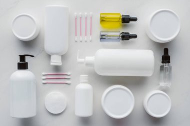 flat lay with bottles of cream, natural oils and cotton swabs on white surface, beauty concept