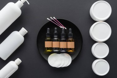 krema, doğal yağlar ve kozmetik yastıkları siyah, güzellik kavramı izole şişe üstten görünüm