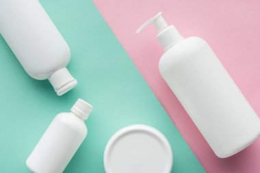 top view of bottles of cream on green and pink surface, beauty concept