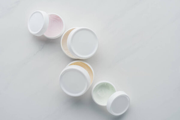 top view of open bottles of cream on white surface, beauty concept