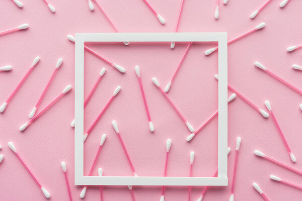 top view of cotton swabs with white frame isolated on pink, beauty concept