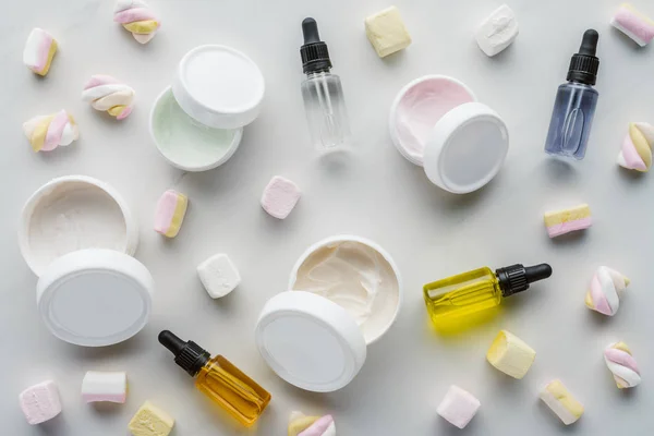 Top view of bottles of cream, natural oils and marshmallows on white surface, beauty concept — Stock Image Top View Bottles Cream Natural Oils Marshmallows White Surface Beauty Royalty Free Stock Photos